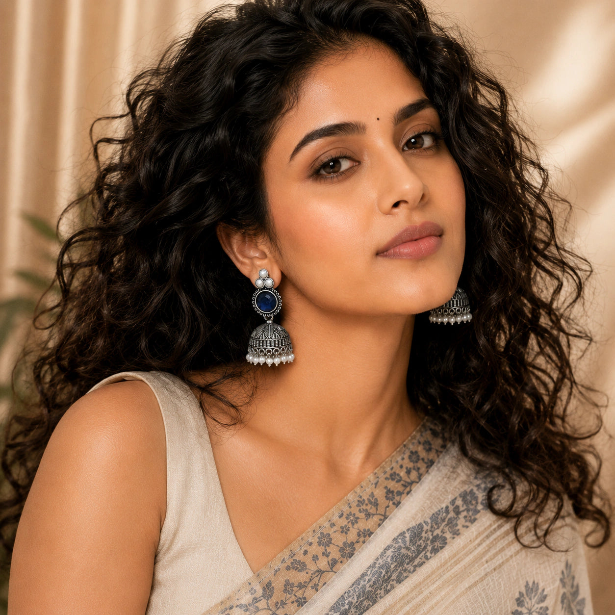 Navy blue pearl-style dome jhumka earrings styled in a jewellery flat lay