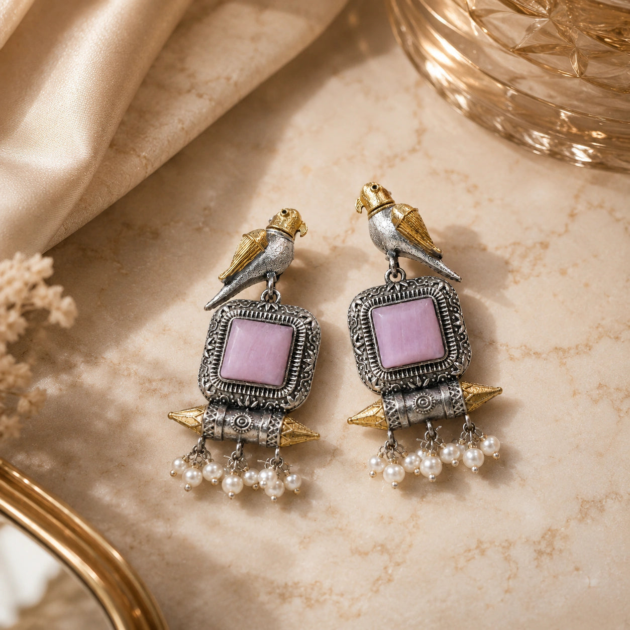 Pink-stone bird pearl dangle earrings styled in an elegant jewellery flat lay