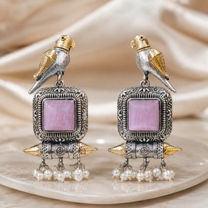 Close-up of pink stones, bird motifs and pearl-style dangle detailing