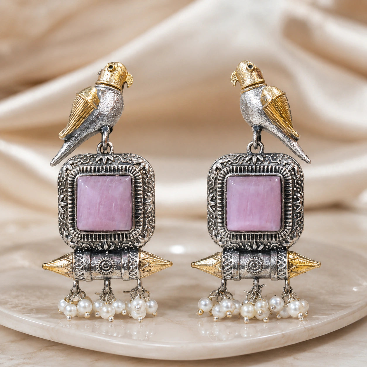 Close-up of pink stones, bird motifs and pearl-style dangle detailing