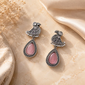 Angled view of German silver pink teardrop bird pearl-style dangle earrings