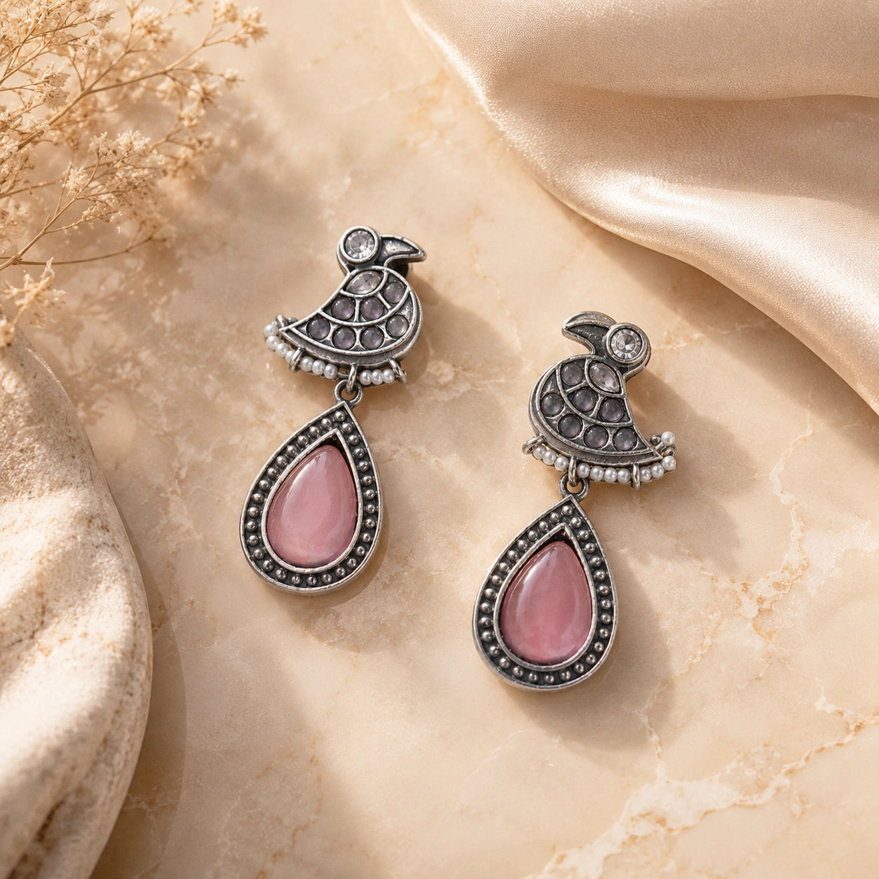 Angled view of German silver pink teardrop bird pearl-style dangle earrings
