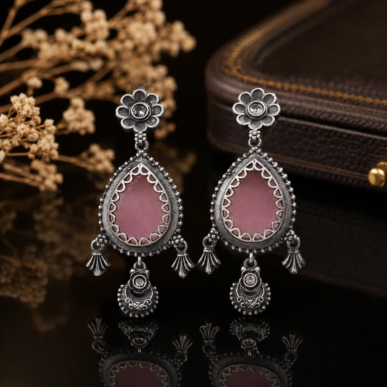 Pink teardrop floral dangle earrings on a dark jewellery studio display