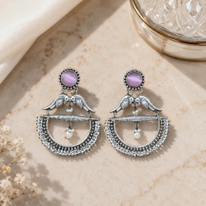 Purple bird pearl chandelier earrings on a dark jewellery studio display