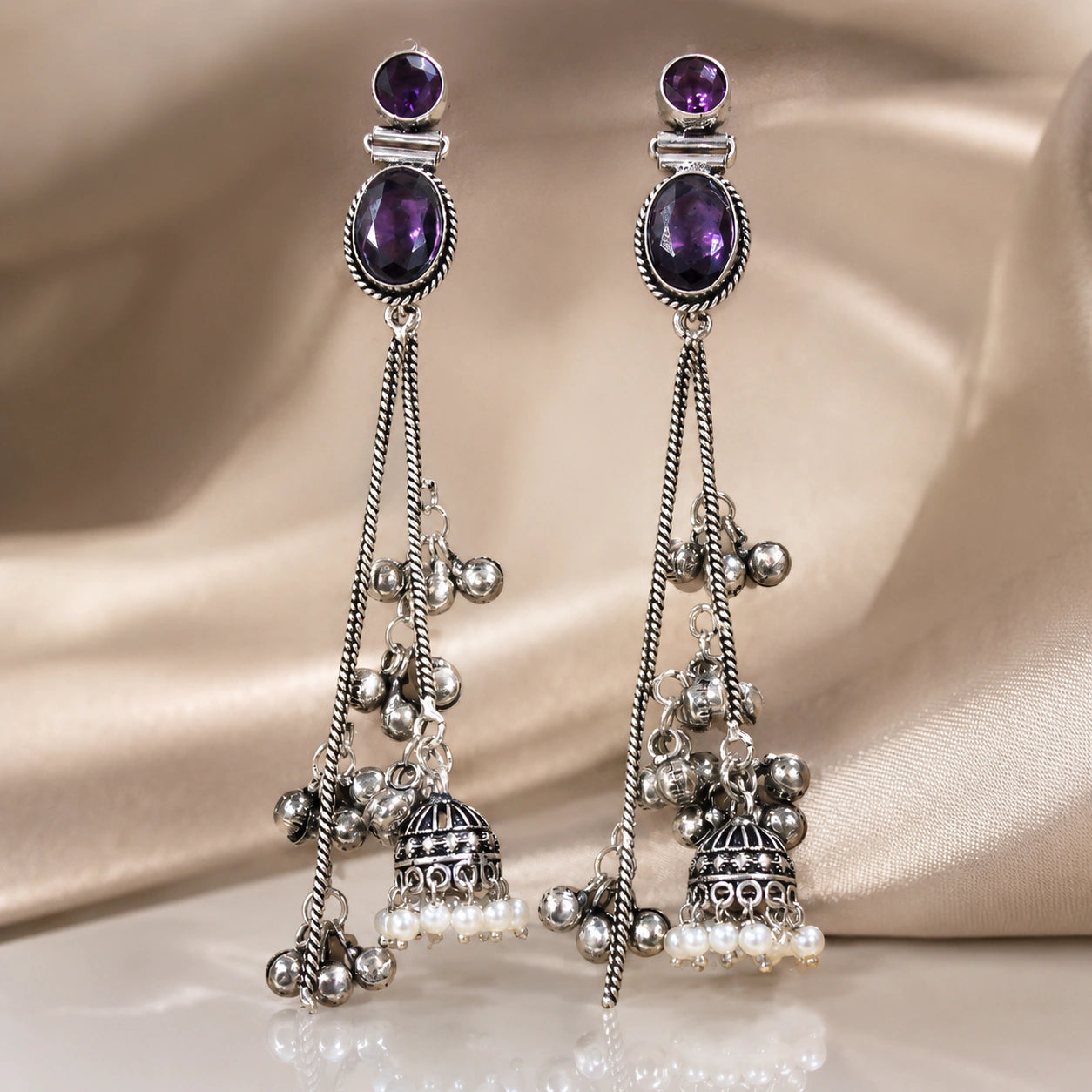 Purple pearl chandelier earrings on a dark jewellery studio display