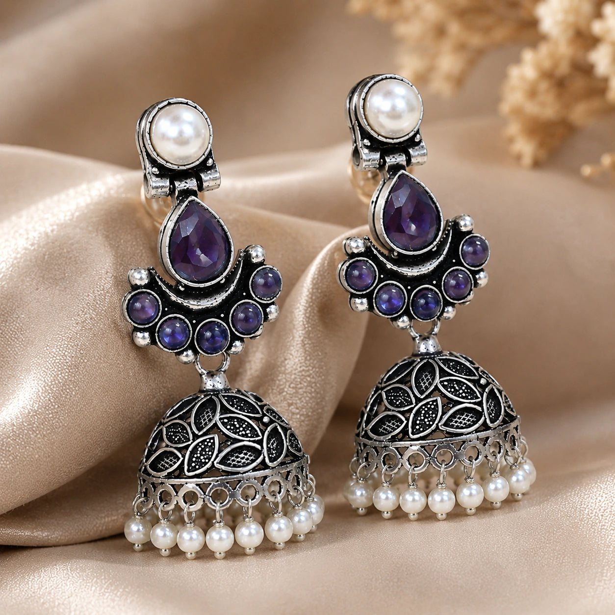 Angled view of German silver purple pearl leaf dome jhumka earrings
