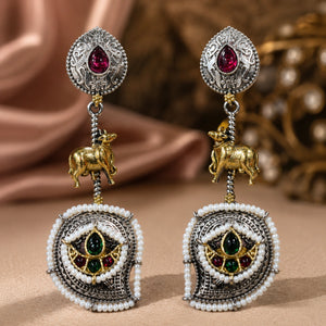 Angled view of German silver rani pink cow charm chandelier earrings