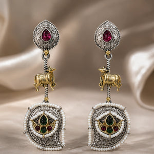 Rani pink cow charm chandelier earrings on a dark jewellery studio display