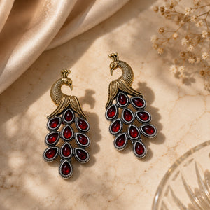 German silver red peacock chandelier earrings styled in a jewellery flat lay