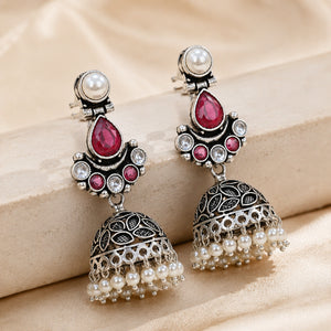 Ruby-tone pearl leaf jhumka earrings styled in an elegant jewellery flat lay