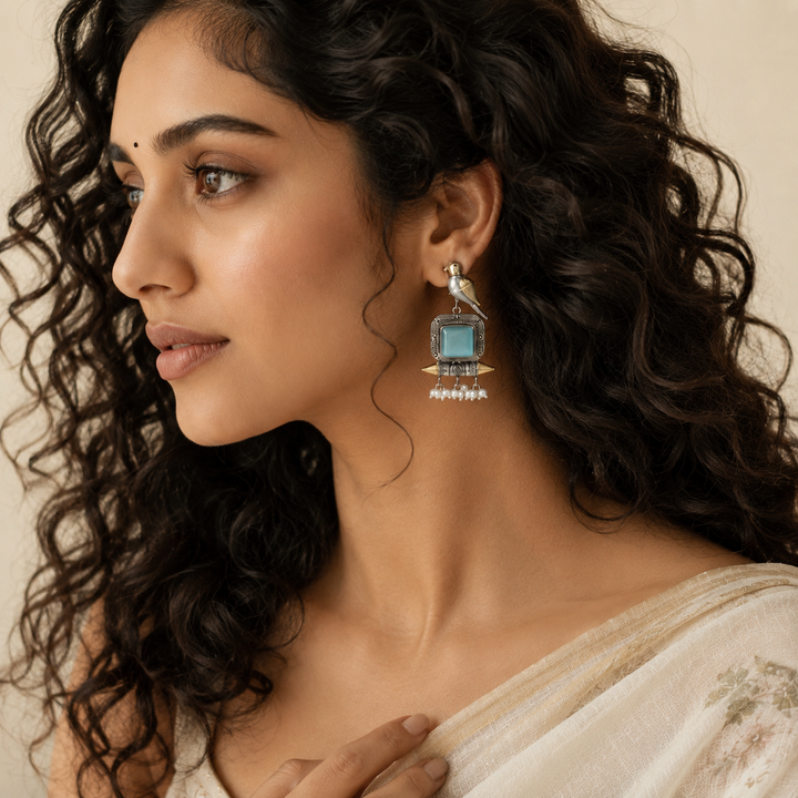 Close-up of sky blue accents, bird motifs and pearl-style dangle detailing
