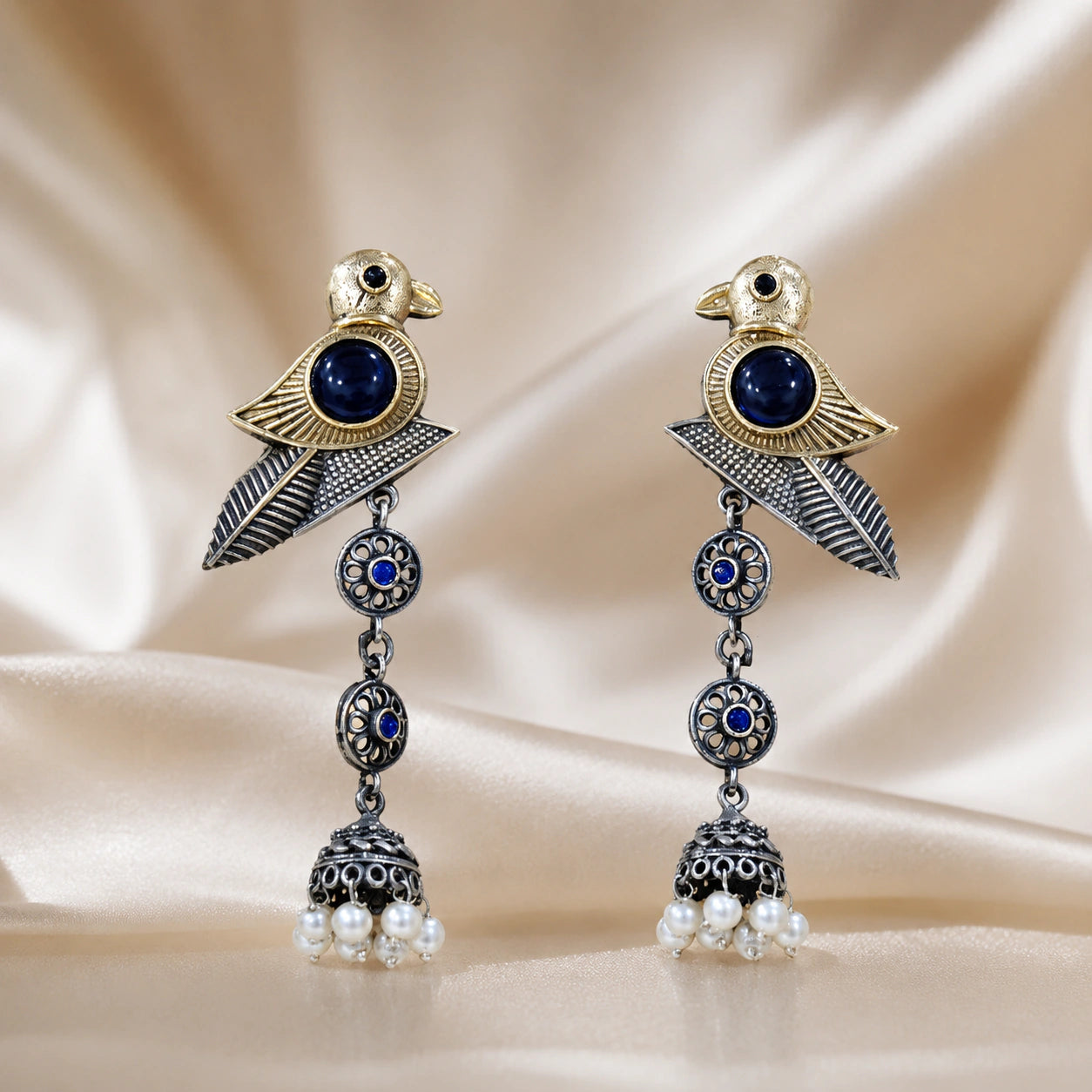 Angled view of German silver sparrow earrings with pearl-style jhumka drops
