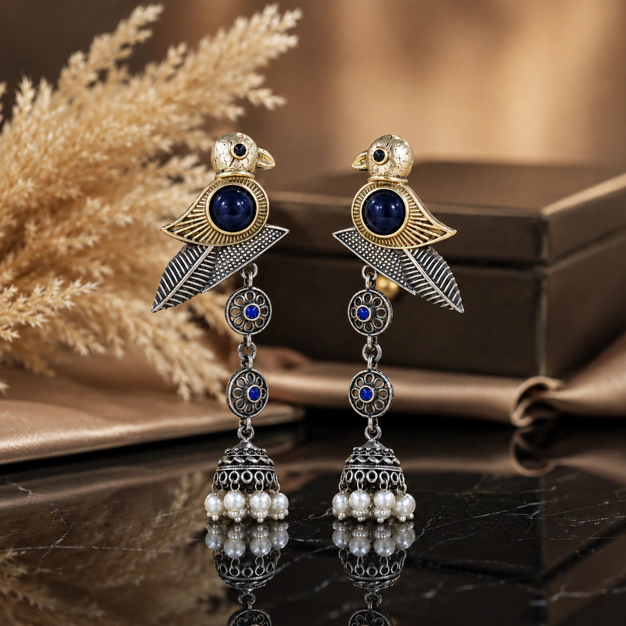 Sparrow pearl-style jhumka earrings on a glossy dark reflective jewellery display