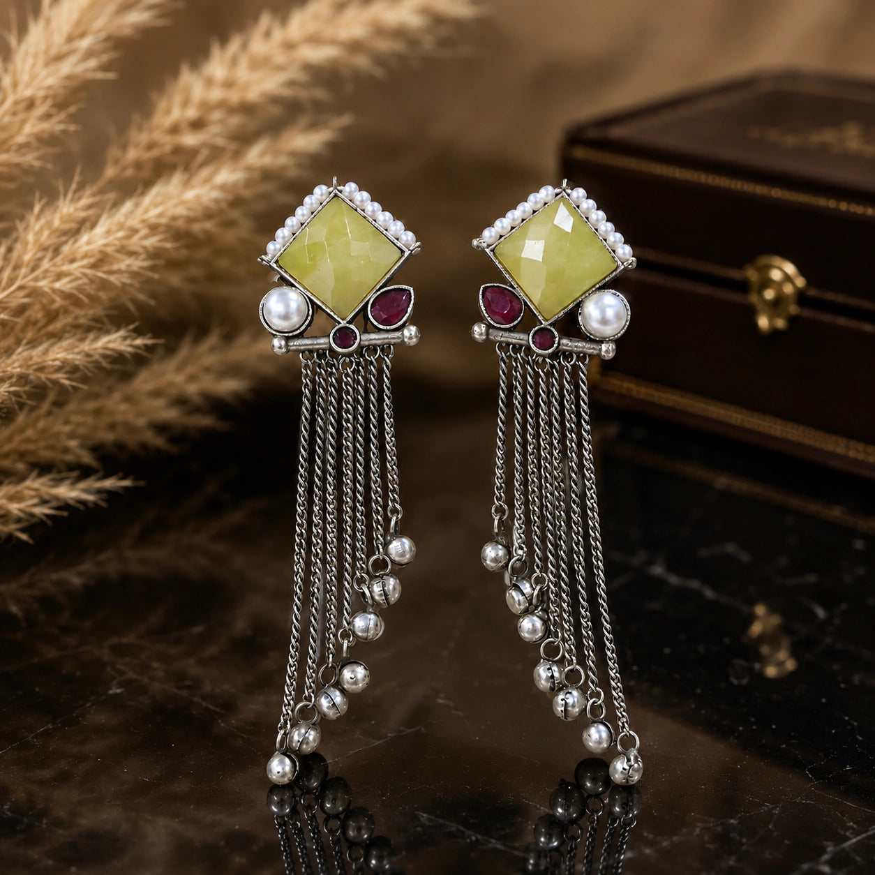 Yellow and maroon pearl-style fringe earrings on a glossy dark jewellery display