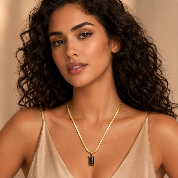 Gold black rectangular stone necklace on a dark jewellery studio display