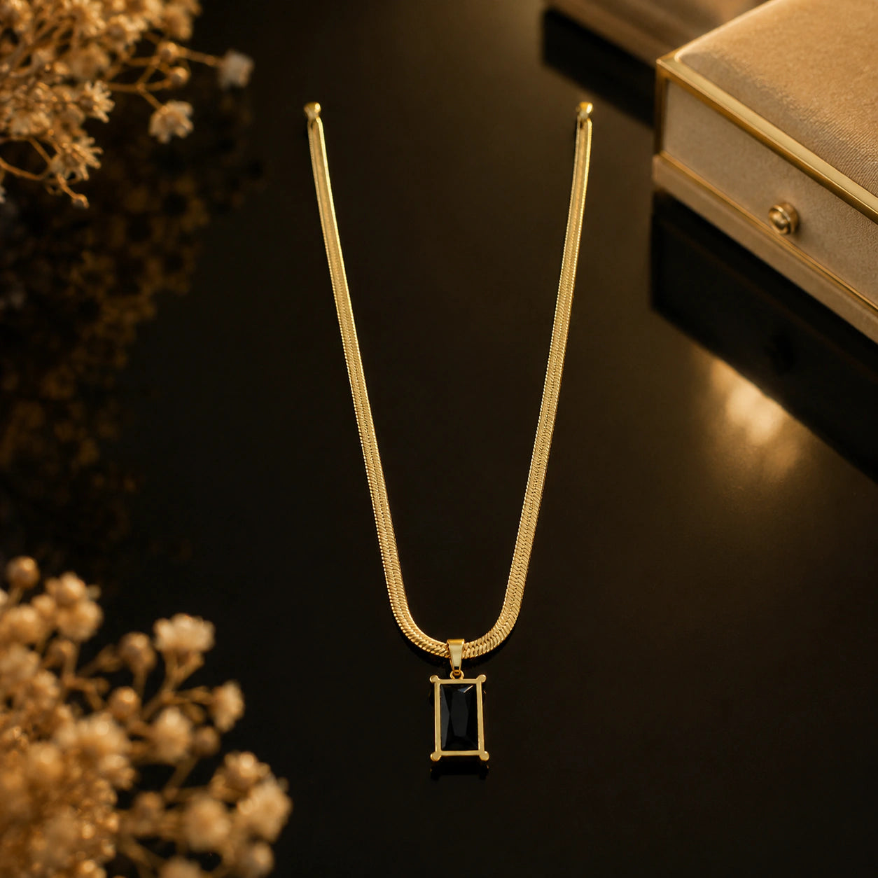 Gold black stone necklace styled in an elegant jewellery flat lay