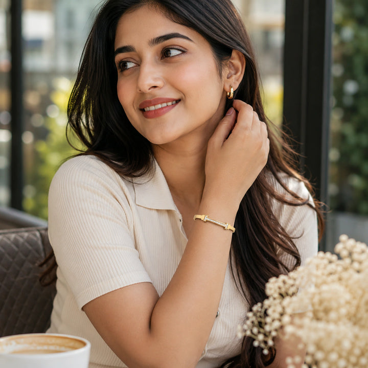 Gold crystal-bar rigid bangle on a dark jewellery studio display