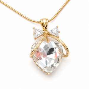 Gold crystal heart bow necklace on a dark jewellery studio display
