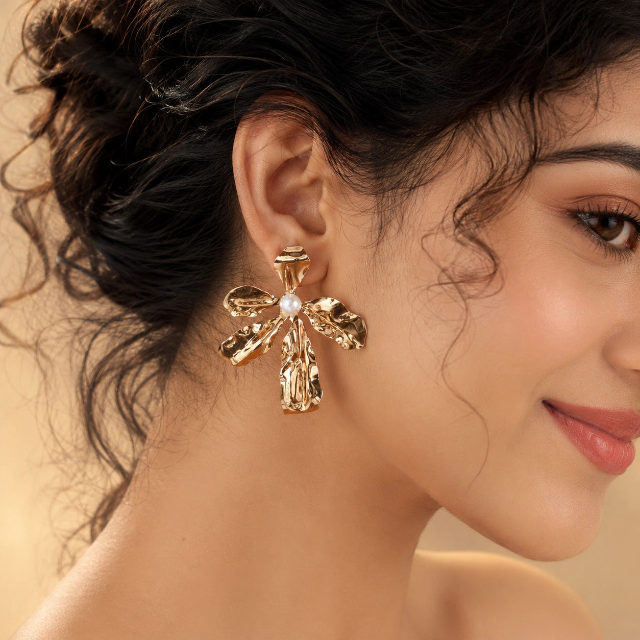 Angled view of gold floral pearl statement drop earrings