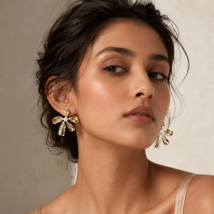 Gold floral pearl statement earrings on a dark jewellery studio display