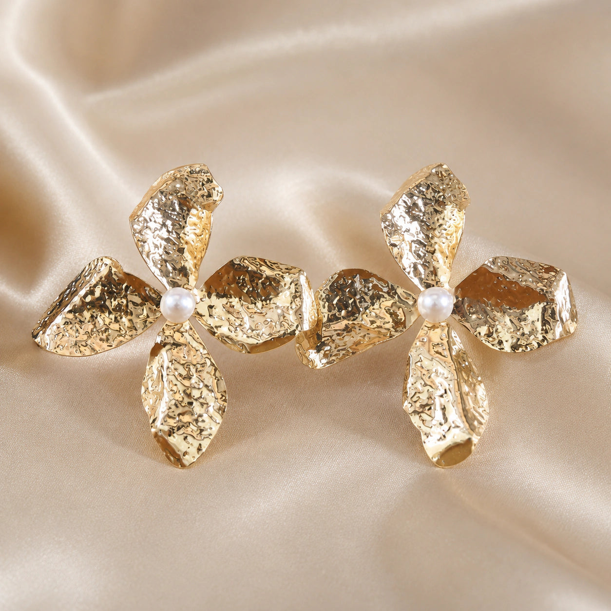 Angled view of gold hammered floral pearl drop earrings