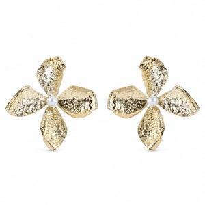Gold hammered floral pearl earrings on a dark jewellery studio display