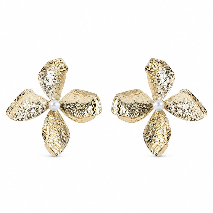 Gold hammered floral pearl earrings on a dark jewellery studio display