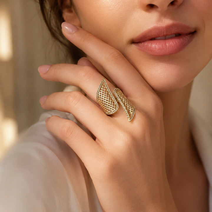 Gold lattice wing ring on a dark jewellery studio display
