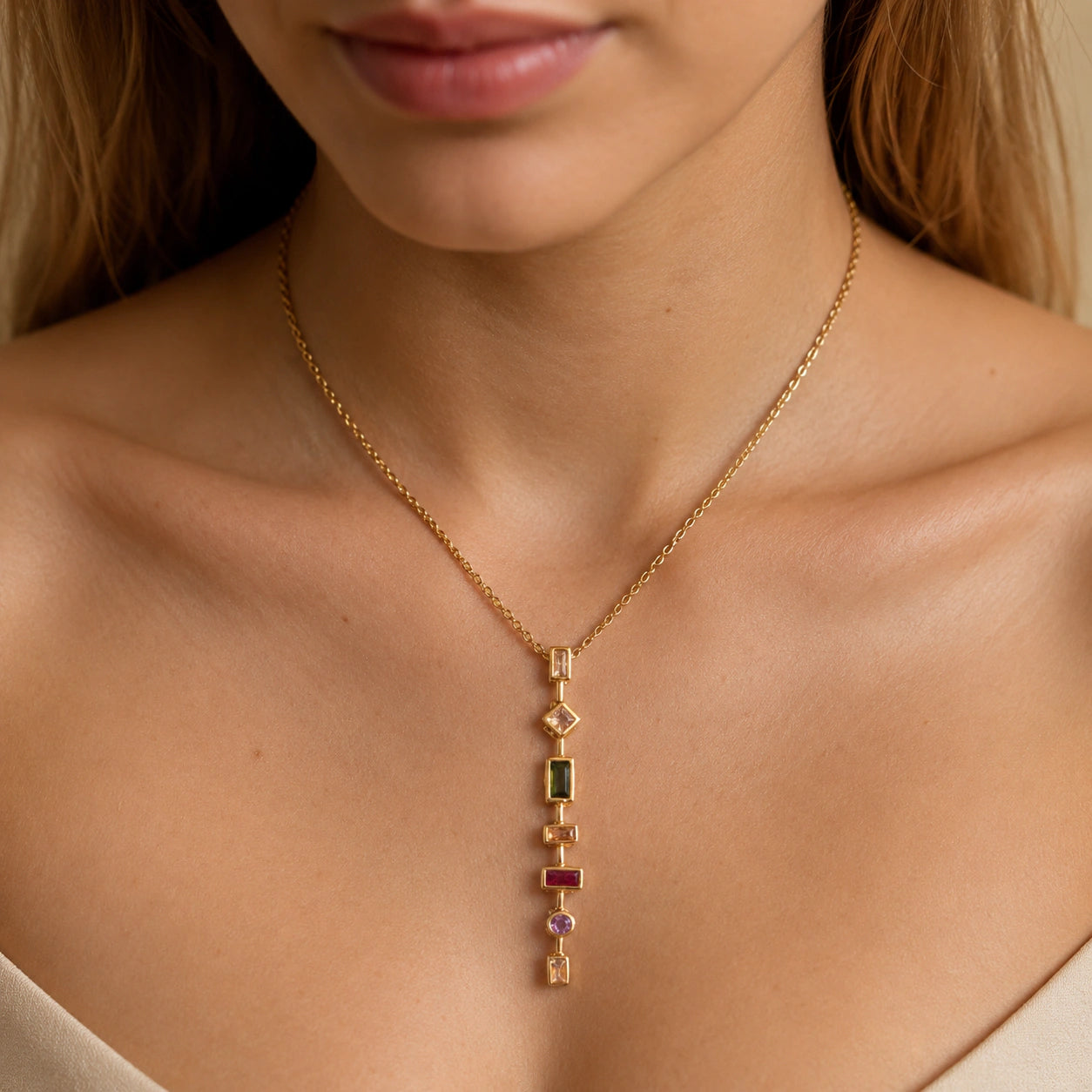 Gold multigem geometric Y necklace on a dark jewellery studio display