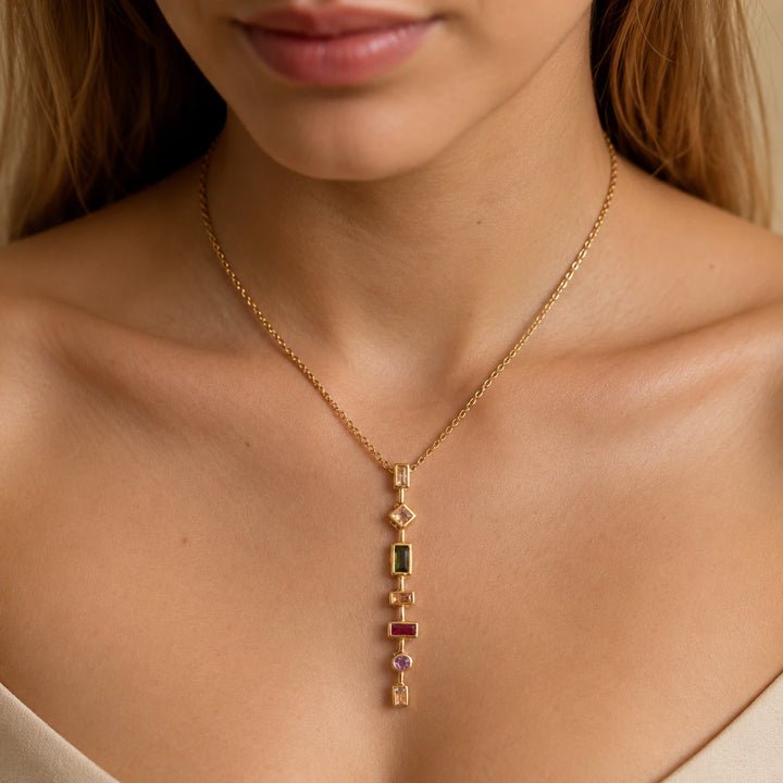 Gold multigem geometric Y necklace on a dark jewellery studio display