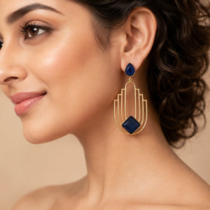 Gold navy geometric chandelier earrings on a dark jewellery studio display
