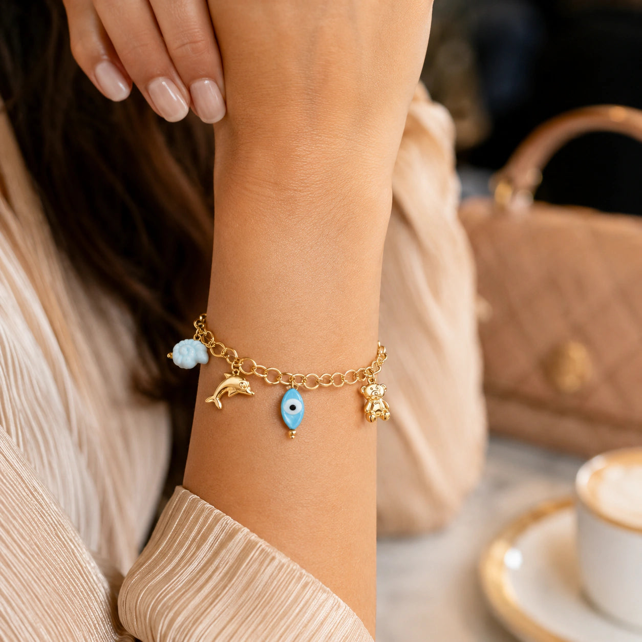 Gold ocean charm bracelet styled in a beach-inspired jewellery flat lay