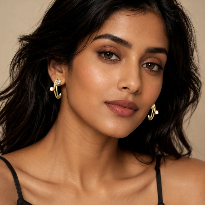 Gold open cuff hoop earrings on a dark jewellery studio display