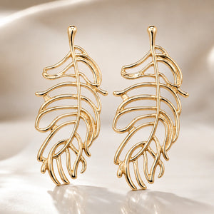 Gold tropical leaf earrings styled in an elegant jewellery flat lay