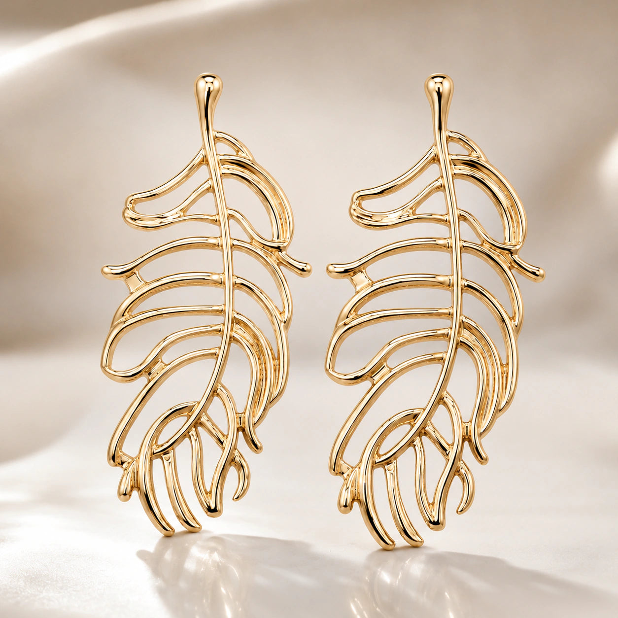Gold tropical leaf earrings styled in an elegant jewellery flat lay