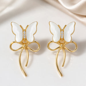 Gold butterfly bow earrings styled in an elegant jewellery flat lay
