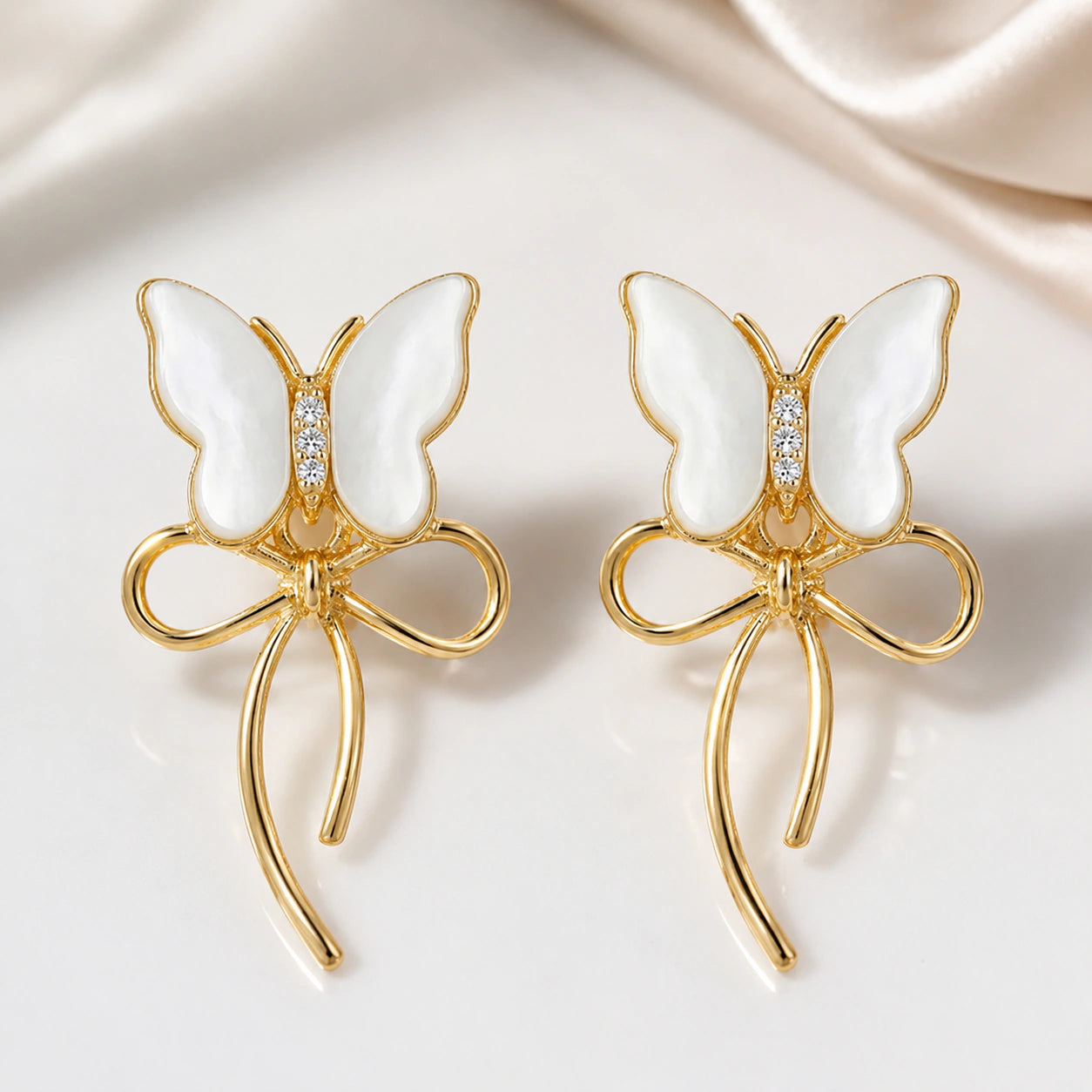 Gold butterfly bow earrings styled in an elegant jewellery flat lay