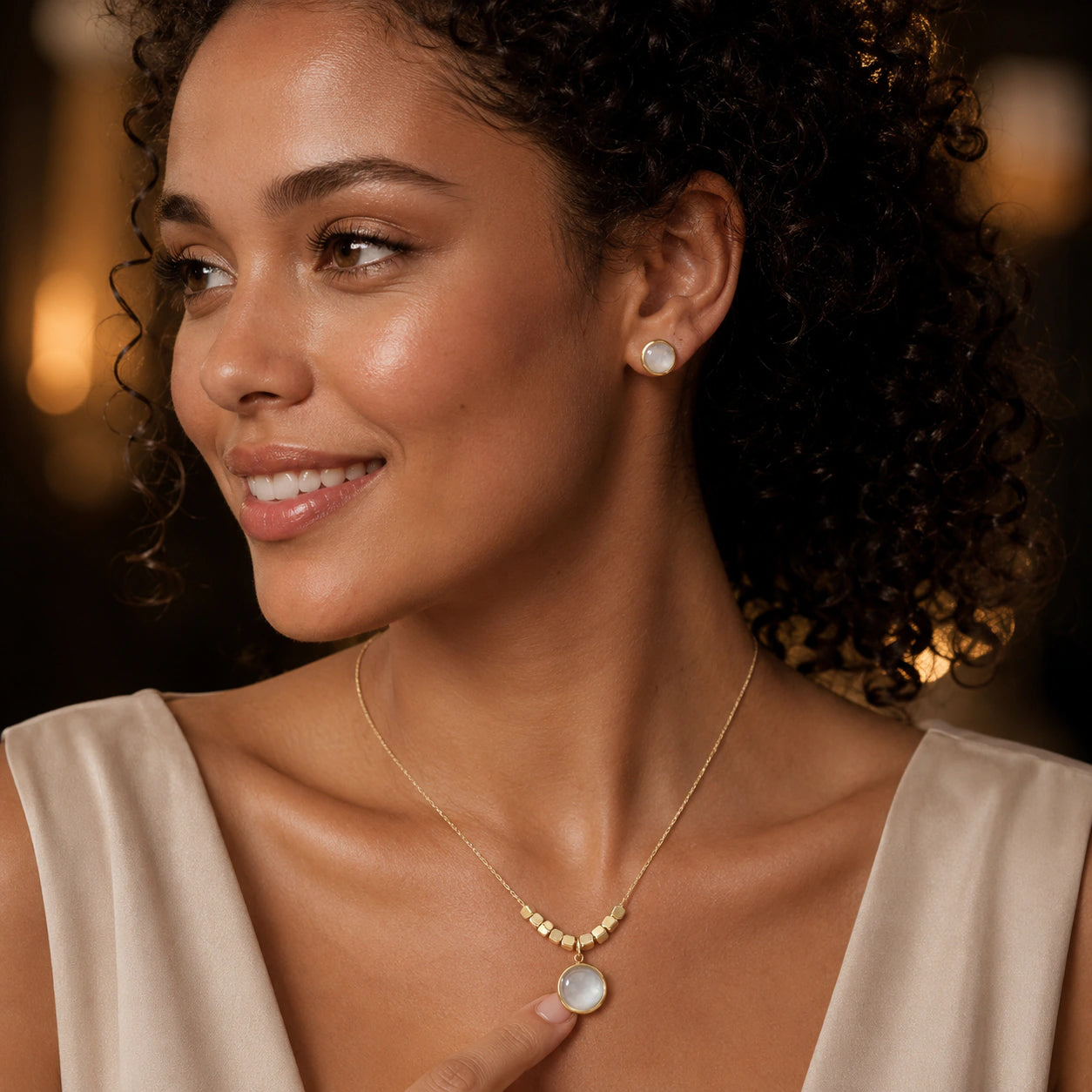 Gold pearl round pendant necklace set on a dark jewellery studio display