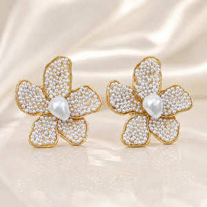 Gold pearl teardrop floral studs styled in an elegant jewellery flat lay