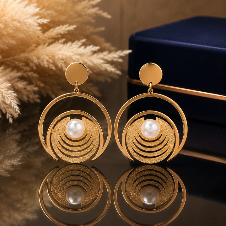 Gold pearl textured hoop earrings on a dark jewellery studio display