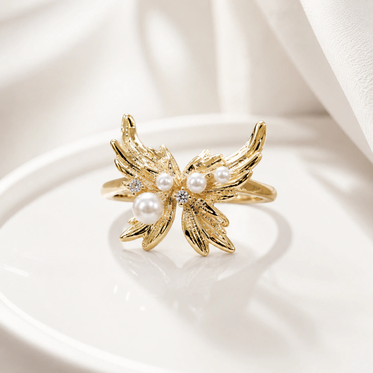 Angled view of the gold pearl wing open ring
