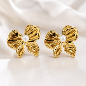 Gold sculpted pearl flower studs styled in an elegant jewellery flat lay