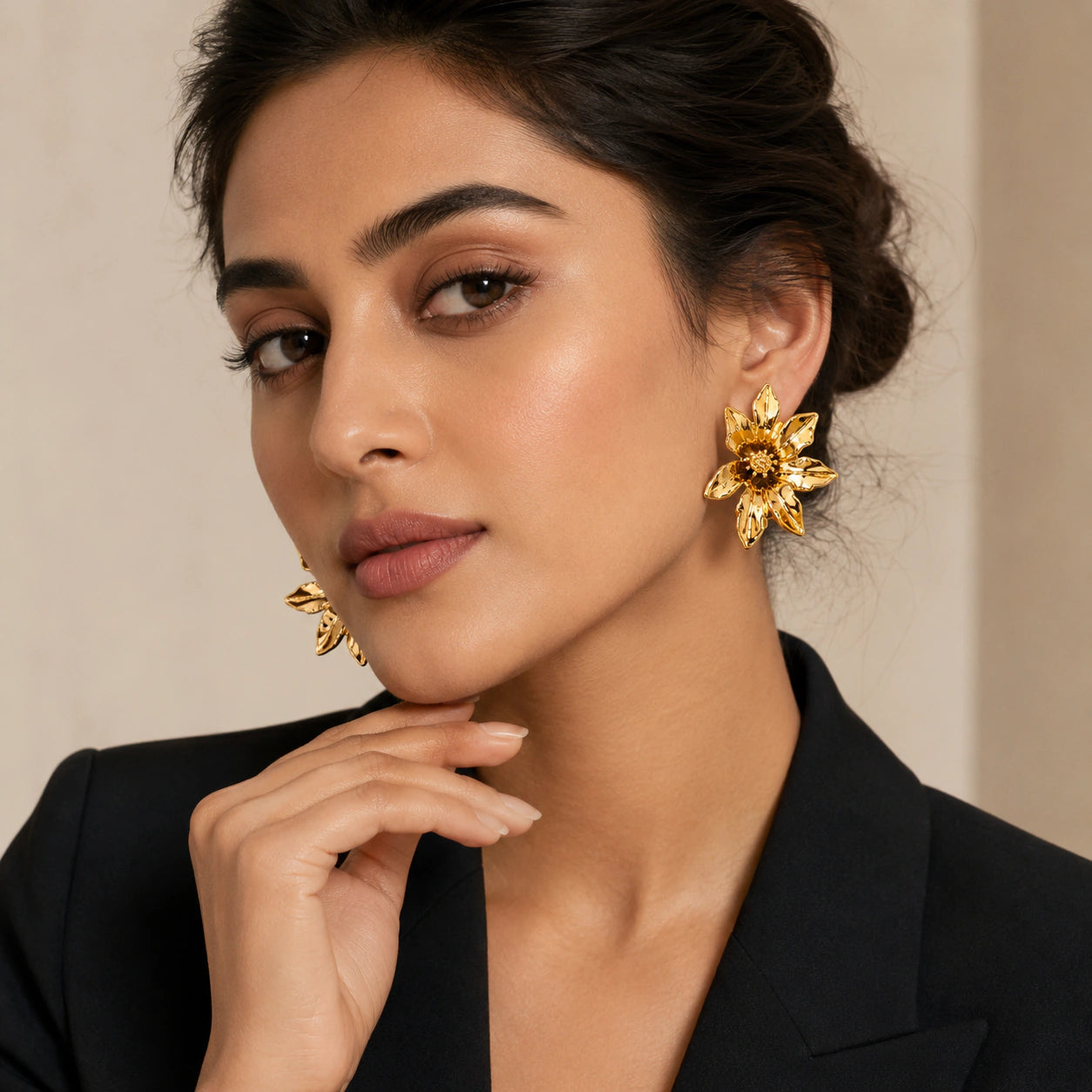 Gold sculptural bloom studs on a dark jewellery studio display