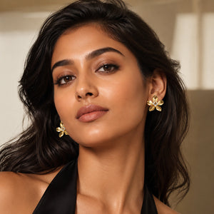 Angled view of gold sculptural flower crystal stud earrings