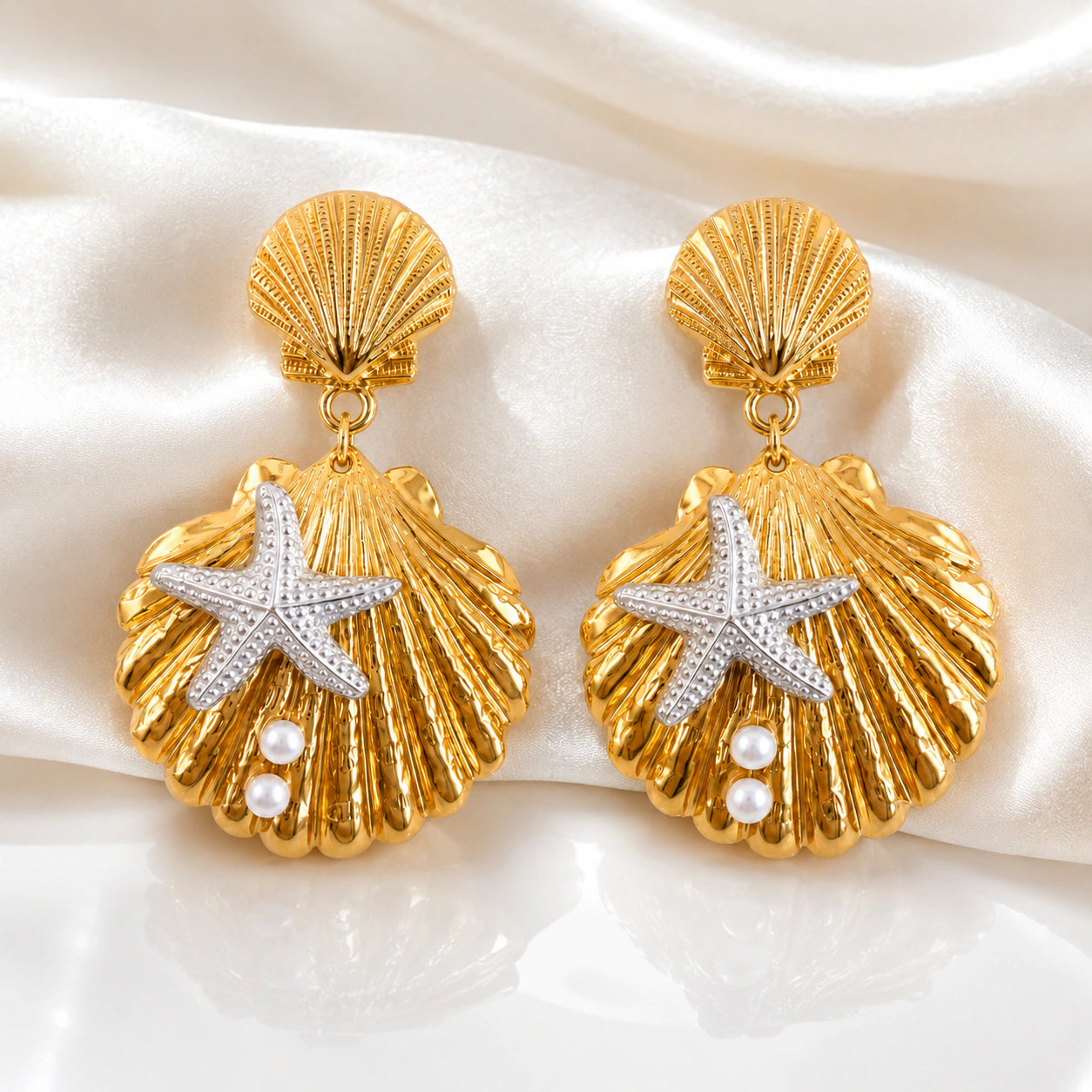 Gold shell starfish earrings styled in a beach-inspired jewellery flat lay