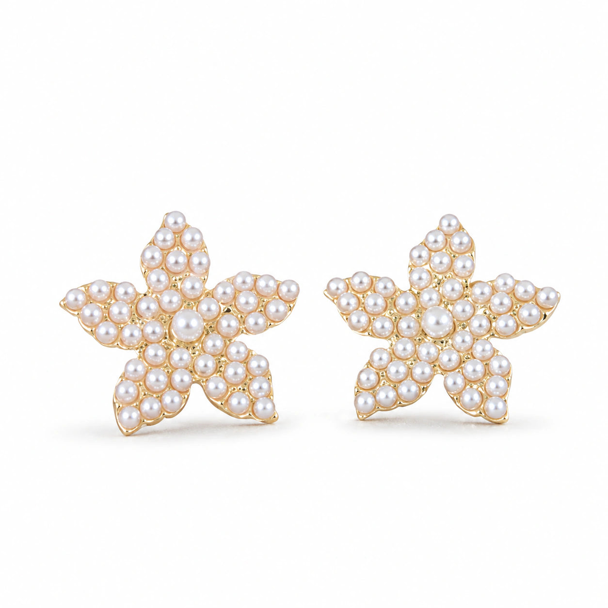 Gold starfish pearl studs styled in a beach-inspired jewellery flat lay
