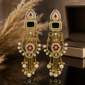 Long green-stone Kundan-style earrings on a glossy dark reflective jewellery display