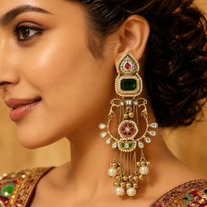 Long green-stone Kundan-style earrings styled in an elegant jewellery flat lay
