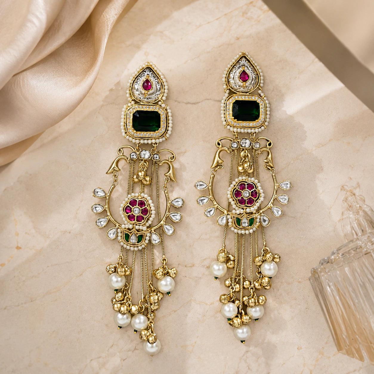 Long gold-tone green-stone Kundan-style statement earrings worn by a model