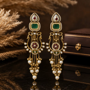 Green-stone pearl chandelier earrings on a glossy dark reflective jewellery display